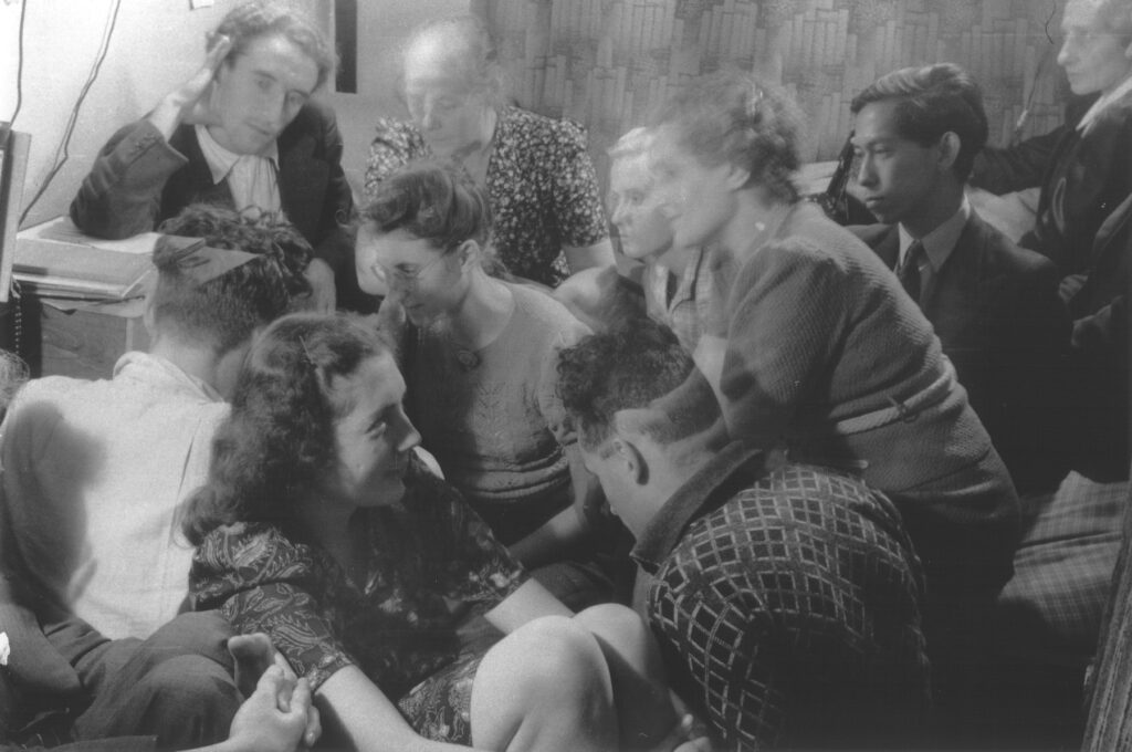 A group of Dutch resistance members and hidden Jews are crowded into a room [possibly to listen to a clandestine radio]. Those pictured include Bep Klant, Rosette Aussen-Muscoviter, Dirk Pos, Benno Aussen, Lizzy Pos and Oey Tjeng Sit